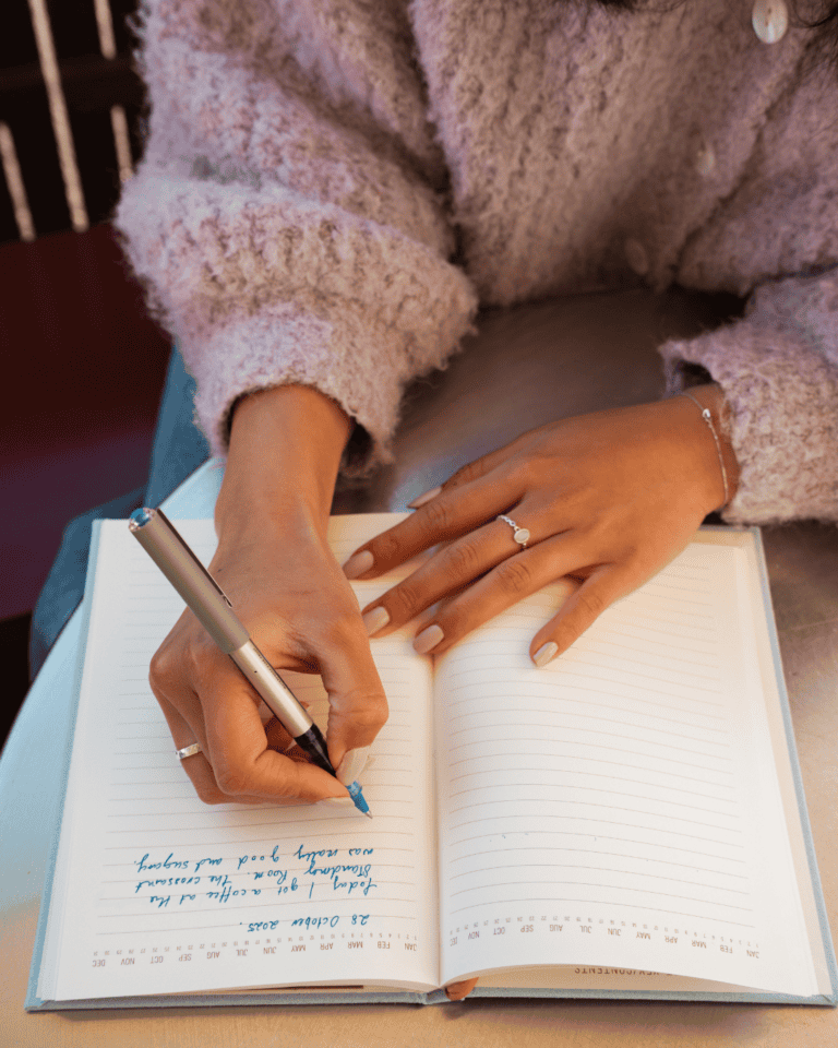 A woman in a pink sweater writes notes in blue ink beta reading